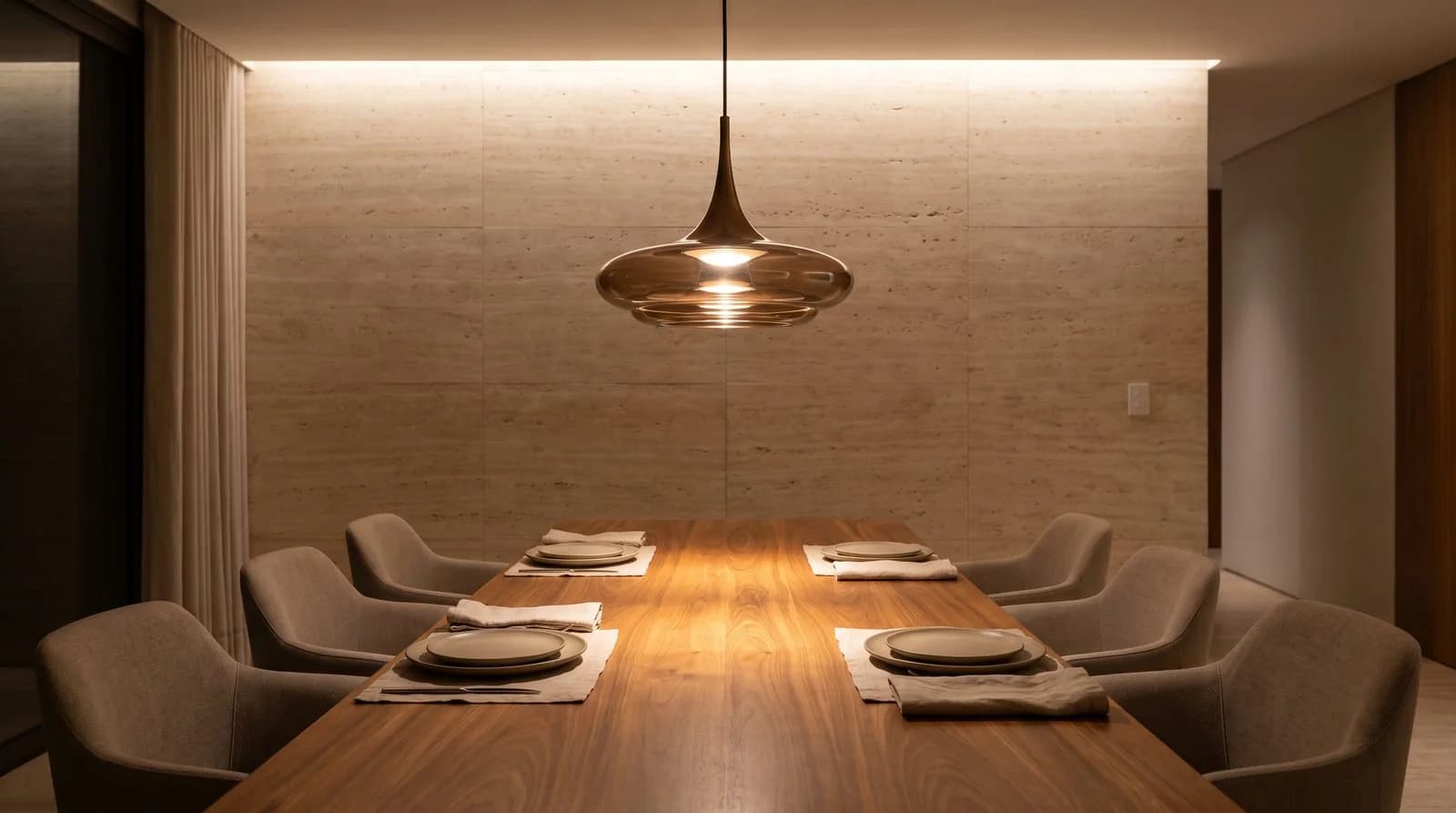 Luminária pendente de vidro instalada centralizada sobre mesa de jantar em madeira com seis cadeiras estofadas.